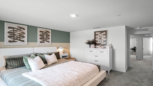 Spacious primary bedroom with king size bed, carpet flooring, natural lighting and a walk in closet.