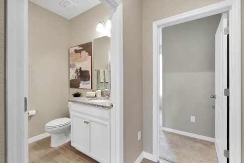 Entrance to modern bathroom with single vanity, large wall mirror, cabinets and granite countertops.