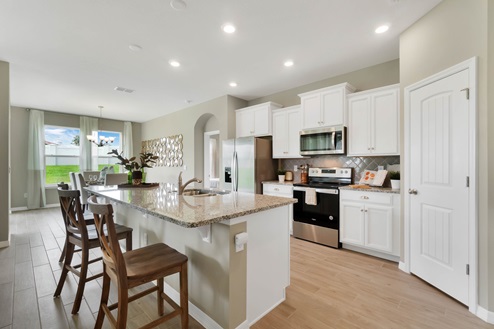 Kitchen with island seating, granite counters, spacious pantry and stainless steel appliances.