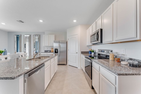 Kitchen with island seating, granite counters, spacious pantry and stainless-steel appliances.