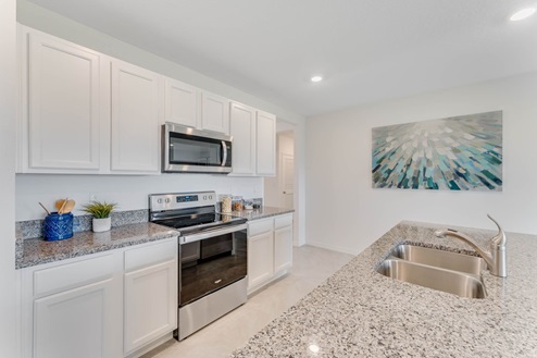 Kitchen with island seating, granite counters, spacious pantry and stainless-steel appliances.
