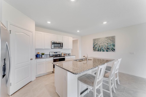 Kitchen with tall cabinetry, appliances, walk in pantry and tile flooring.
