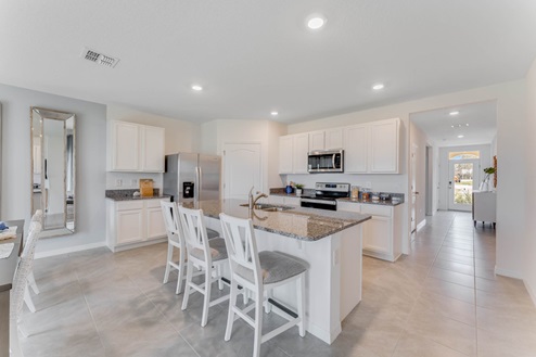 Kitchen with tall cabinetry, appliances, walk in pantry and tile flooring.