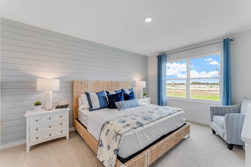 Spacious primary bedroom with king size bed, carpet flooring, natural lighting and a walk in closet.