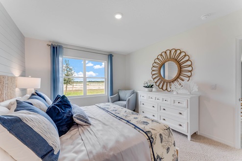 Spacious primary bedroom with king size bed, carpet flooring, natural lighting and a walk in closet.