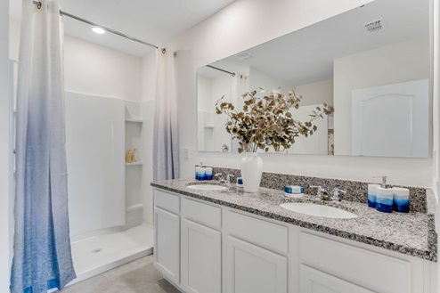 Modern bathroom with double vanity sinks, large wall mirror, cabinets and granite countertops.
