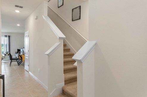 Staircase by entrance hallway with view of living area.