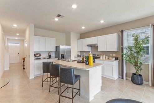 Kitchen with island seating, granite counters, spacious pantry and stainless steel appliance with view of entrance.
