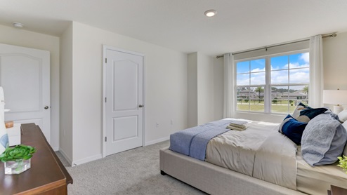 Spacious primary bedroom with king size bed, carpet flooring, natural lighting and a spacious closet.
