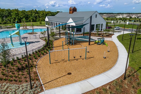 Kids outdoor playground with slide and swings next to pool access.