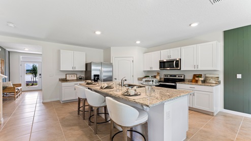 Kitchen with island seating, granite counters, spacous pantry and stainless steel appliances overseeing entry way.