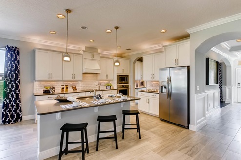 Kitchen with tall cabinetry, appliances, walk in pantry and tile flooring.