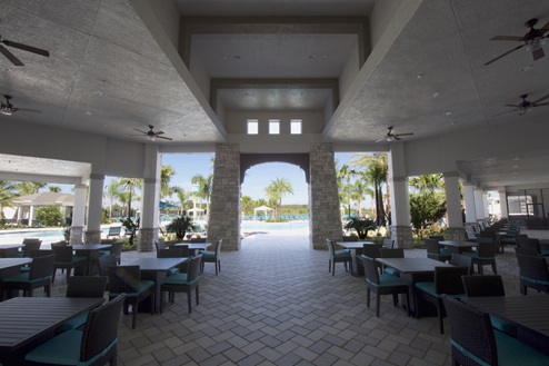 Covered outdoor tables with sitting area showing entrance to clubhouse.