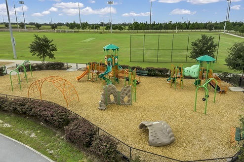 Kids outdoor playground with slide and swings overseeing soccer field.