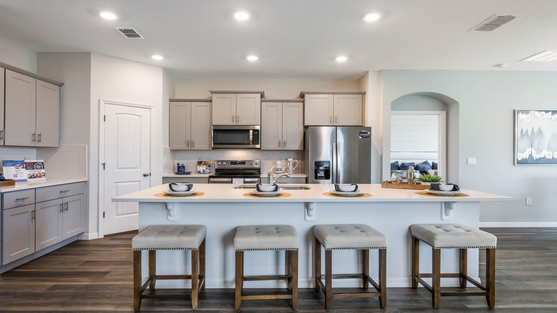 Kitchen with island seating, quartz cpunters, spacious pantry and stainless steel appliances showing entry way to home overseeing primary bedroom
