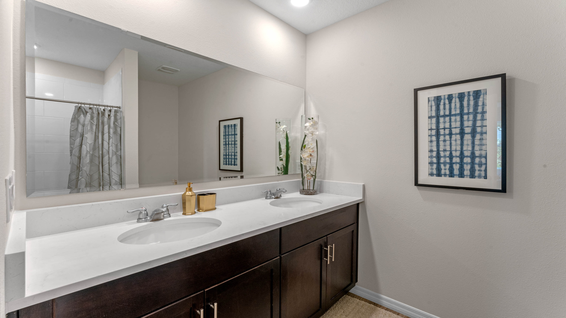 Modern bathroom with double vanity, large wall mirror, cabinets and quartz countertops.
