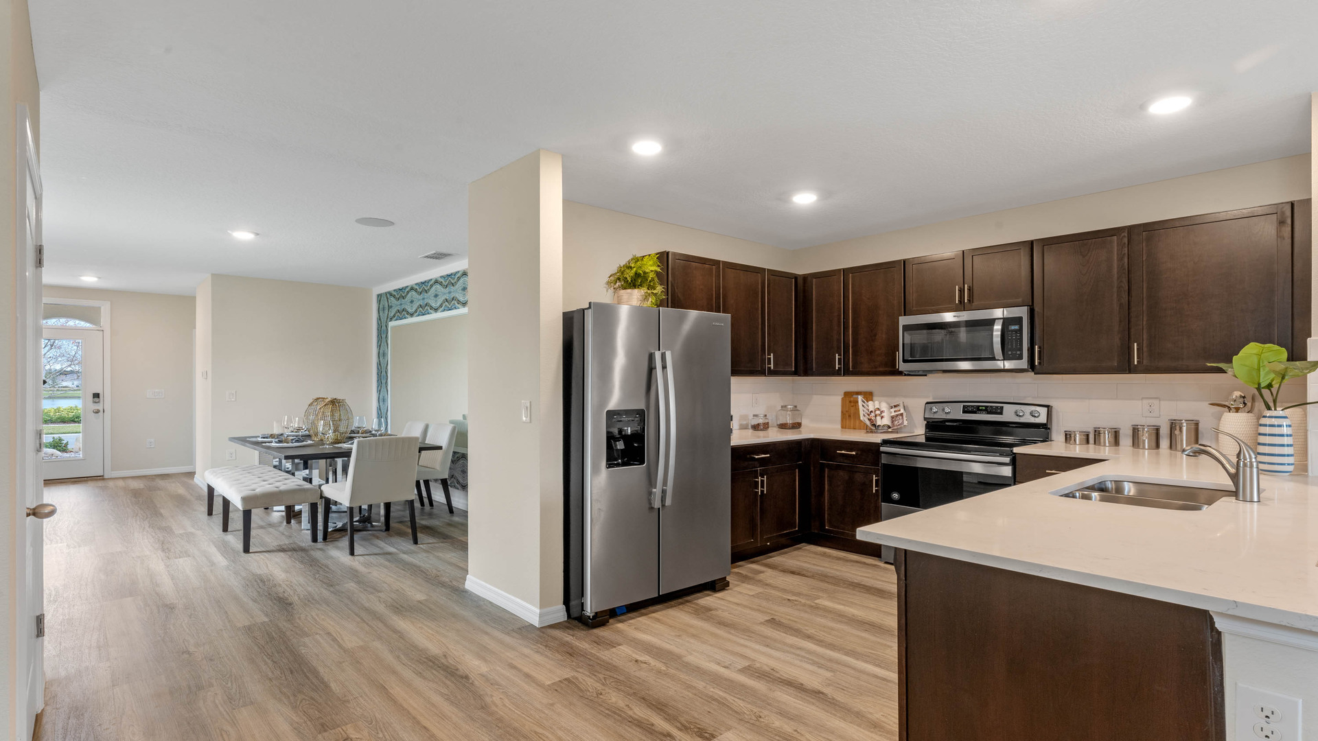 Kitchen with seating, quartz counters, spacious pantry and stainless steel appliances.