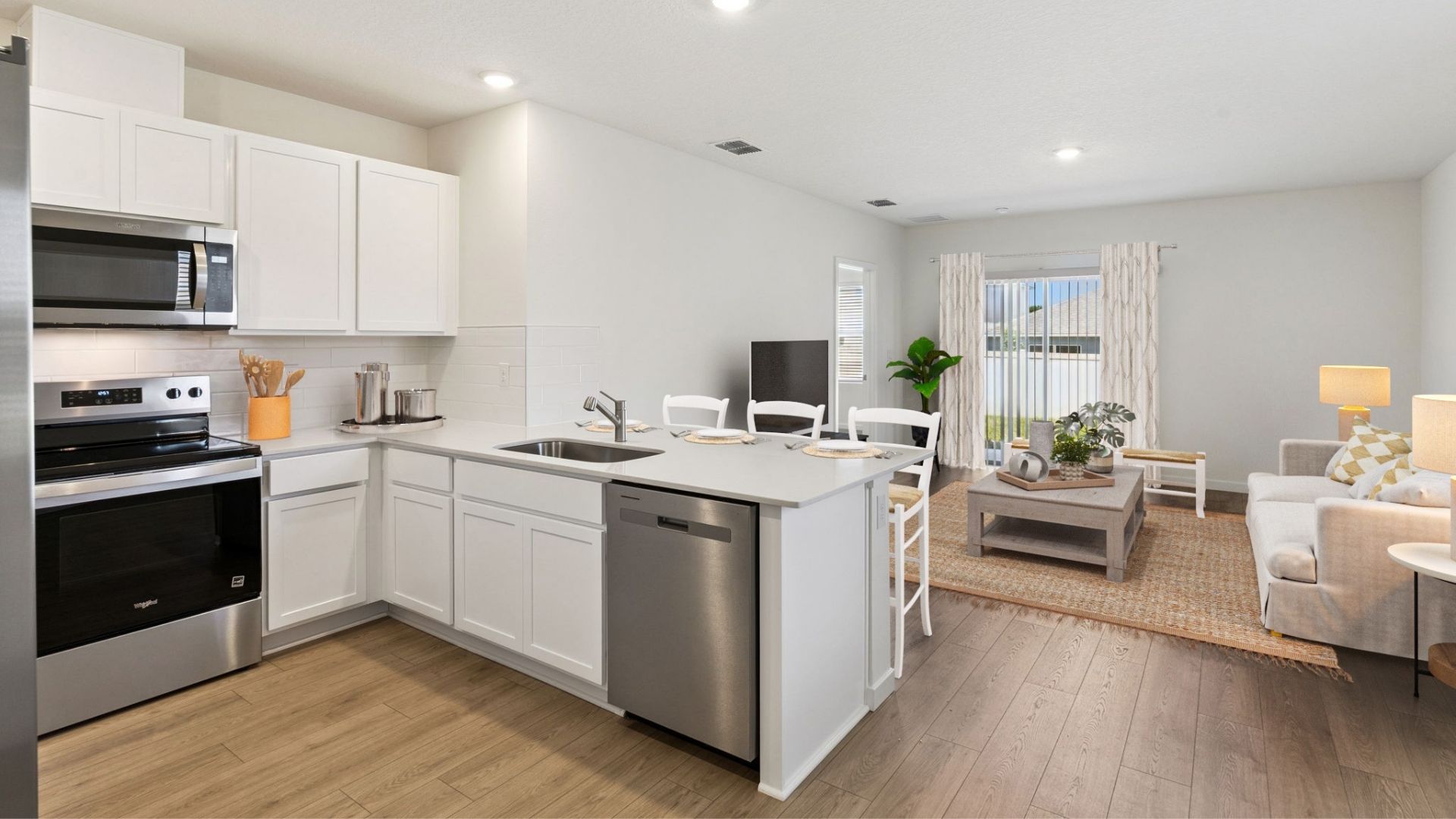 Kitchen with seating, quartz counters, spacious pantry and stainless steel appliances overseeing living area