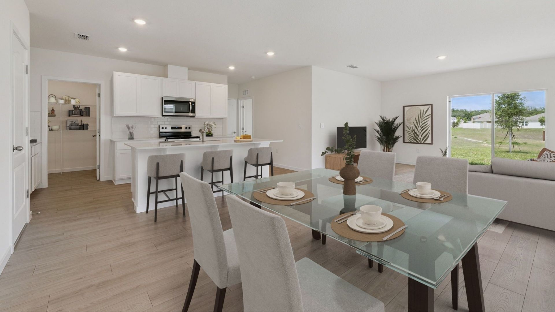 Kitchen with island seating, quartz counters, spacious pantry and stainless steel appliances overseeing dining room and living area