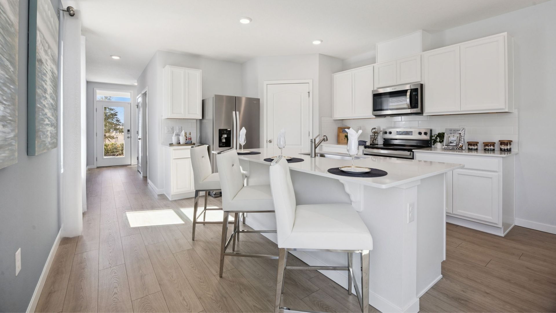 Kitchen with island seating, quartz counters, spacious pantry and stainless steel appliances.
