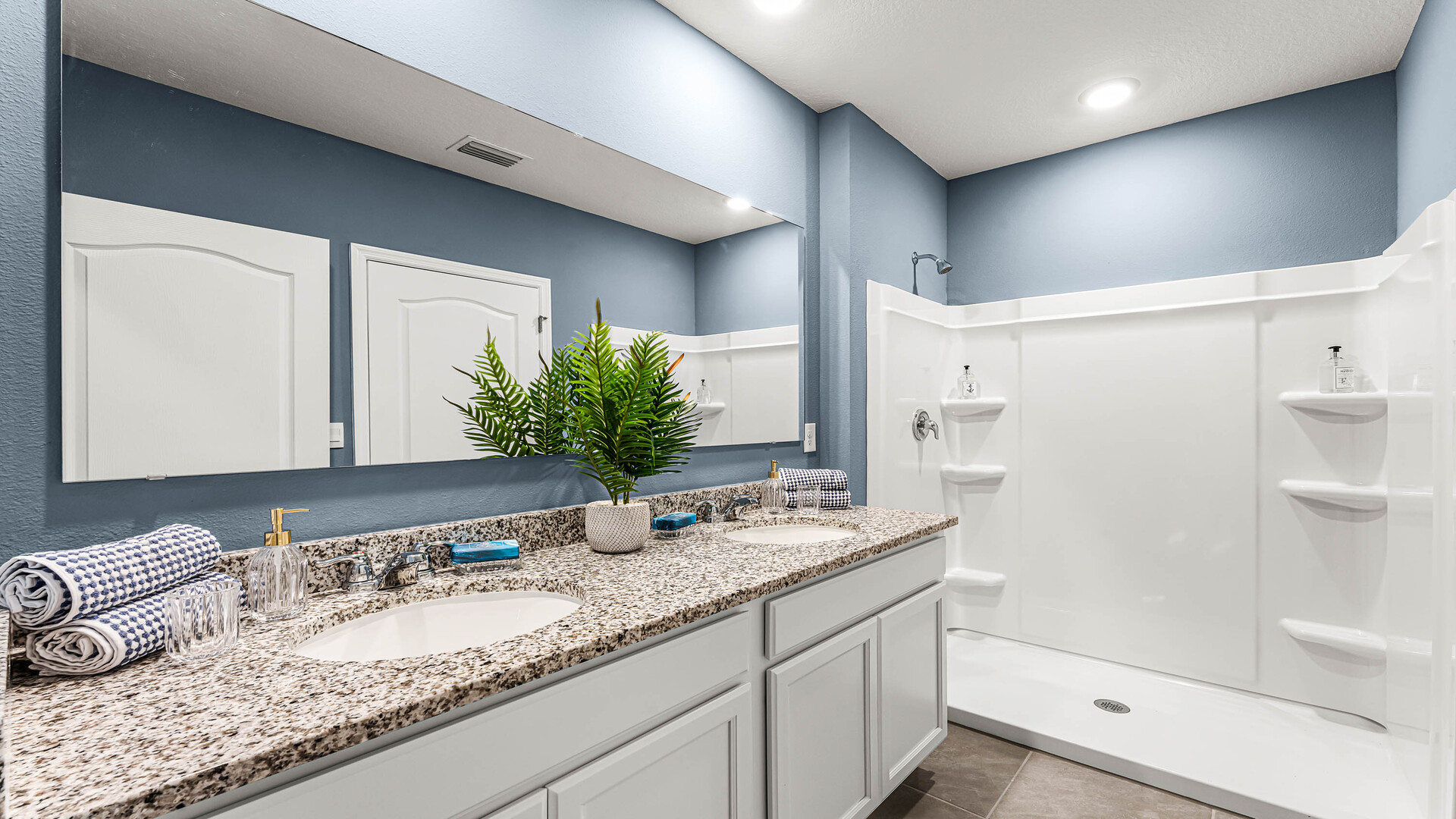 Modern bathroom with single vanity, large wall mirror, cabinets and granite countertops along with toilet and shower