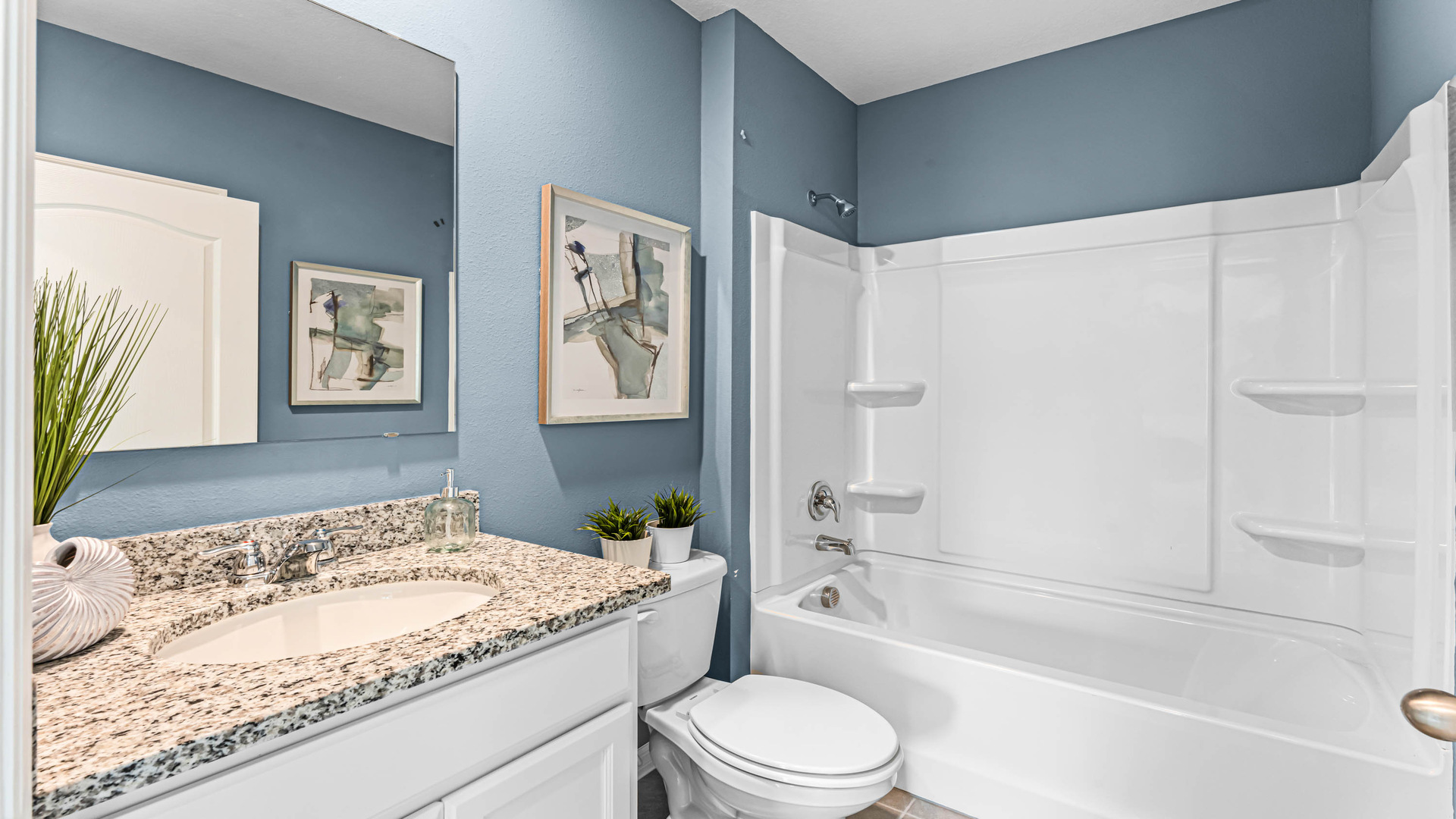 Modern bathroom with single vanity, large wall mirror, cabinets and granite countertops along with toilet and shower