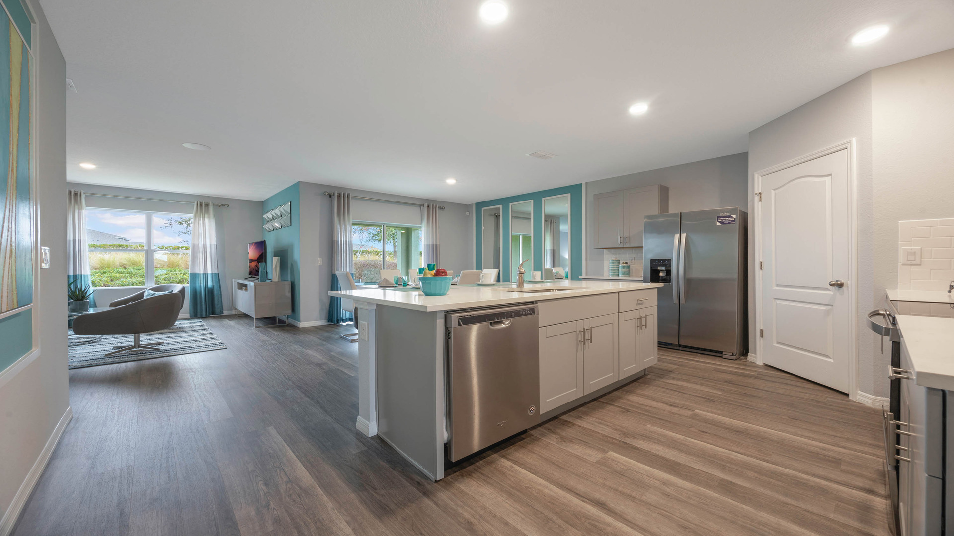 Kitchen with island seating, quartz counters, spacious pantry and stainless steel appliances overseeing dining area.