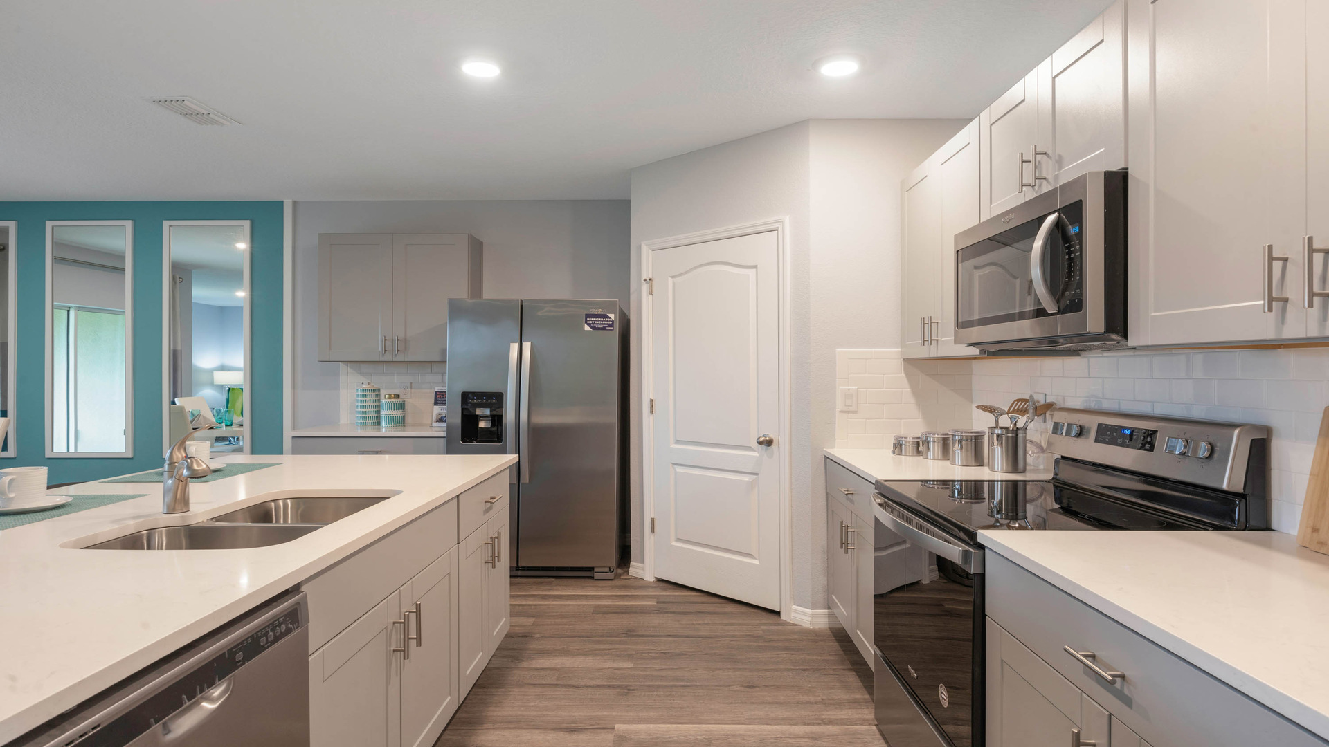 Kitchen with tall cabinetry, appliances, walk in pantry and Luxury vinyl plank flooring.
