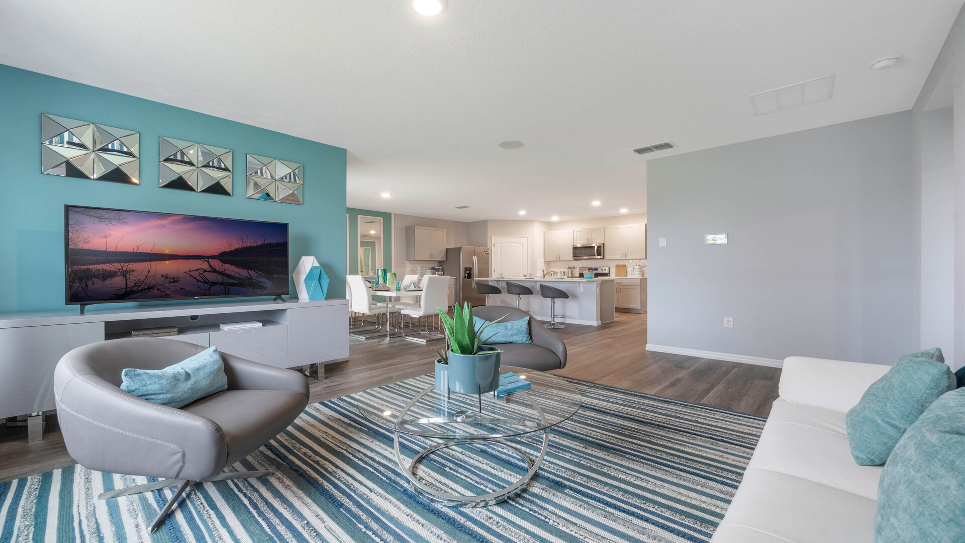 Living area with couch seating, entertainment system and natural lighting overseeing kitchen and dining room