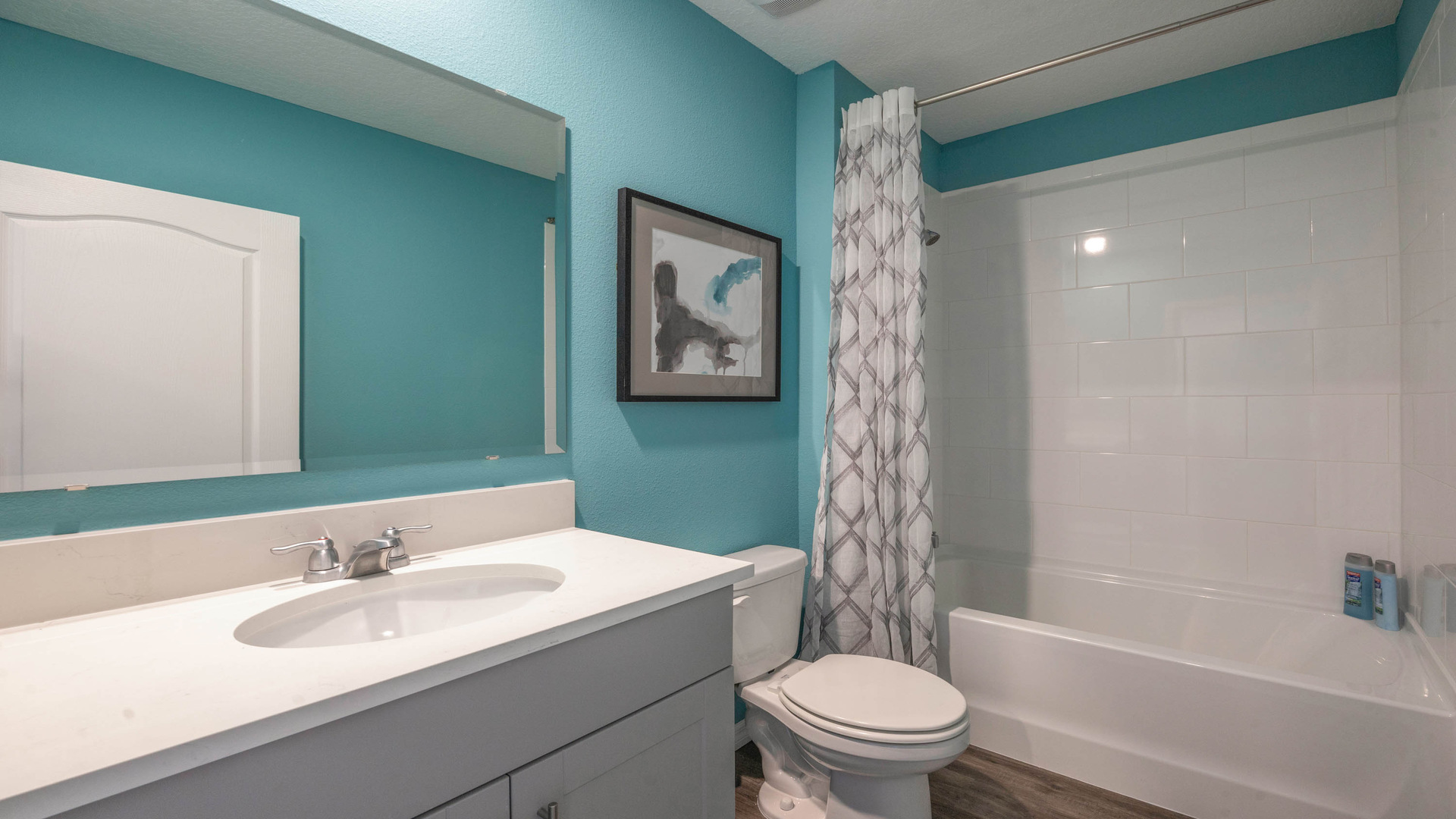 Modern bathroom with single vanity, large wall mirror, cabinets and quartz countertops along with walk-in shower