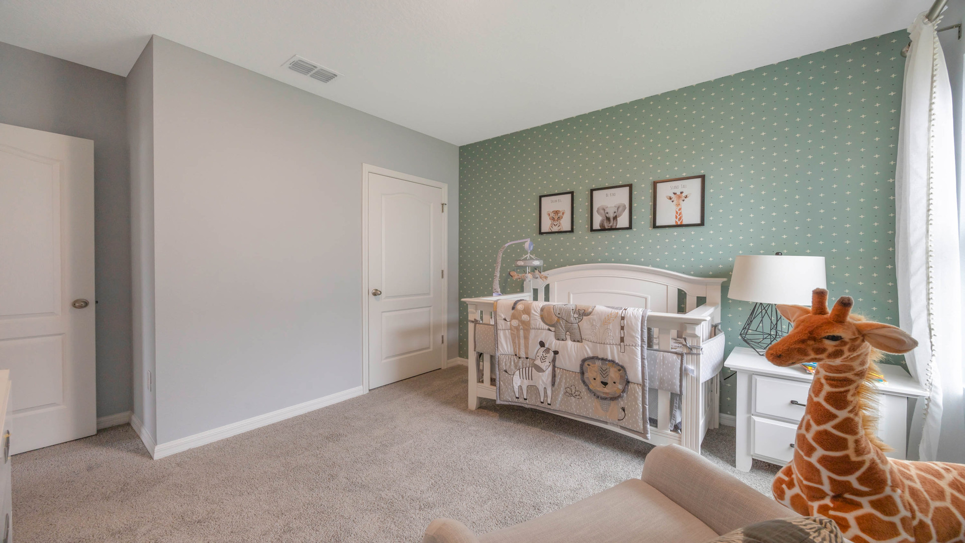Child's nursery with crib, closet, soft seating and storage.