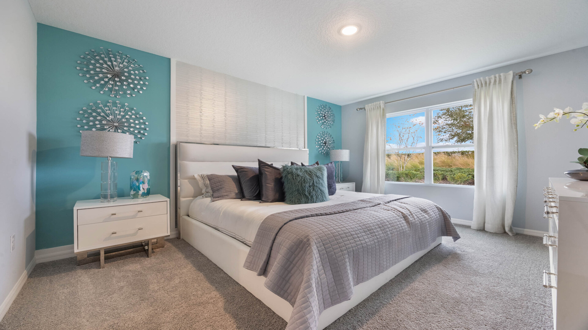 Spacious primary bedroom with king size bed, carpet flooring, natural lighting.