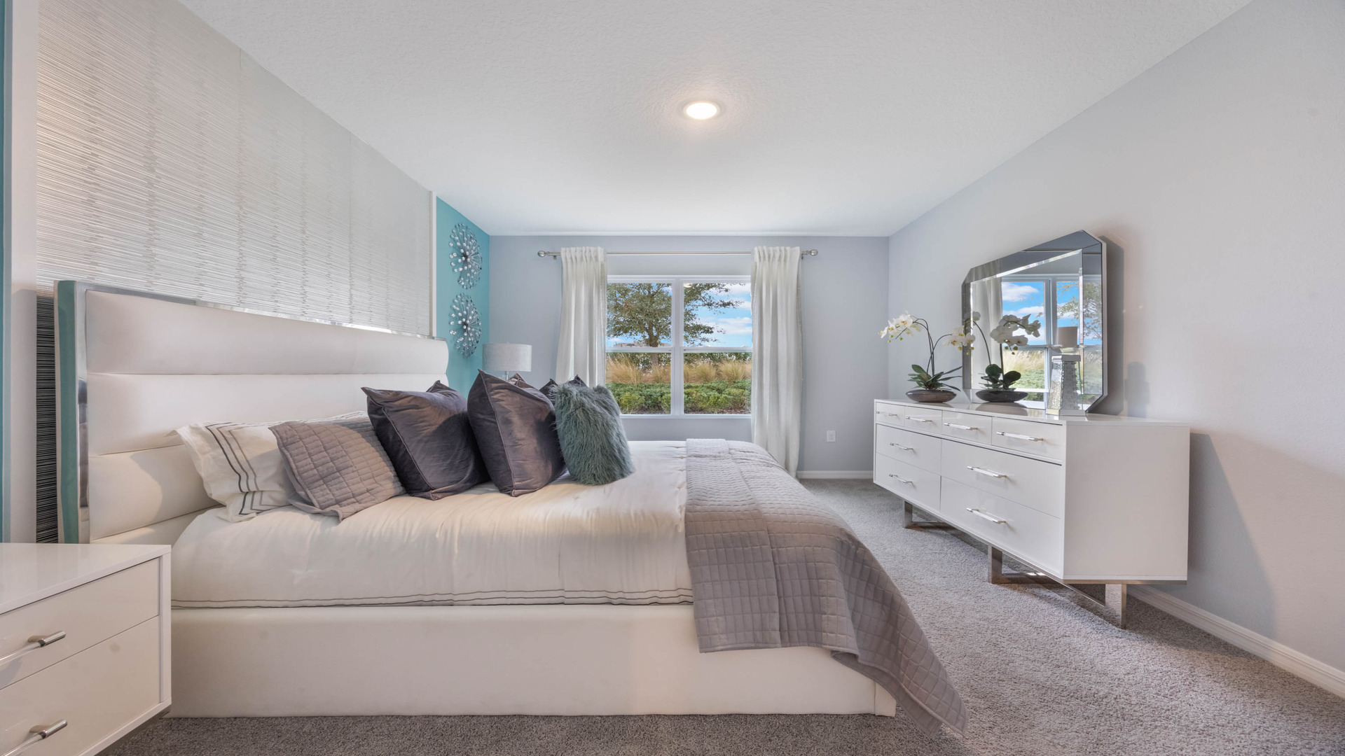 Spacious primary bedroom with king size bed, carpet flooring, natural lighting.