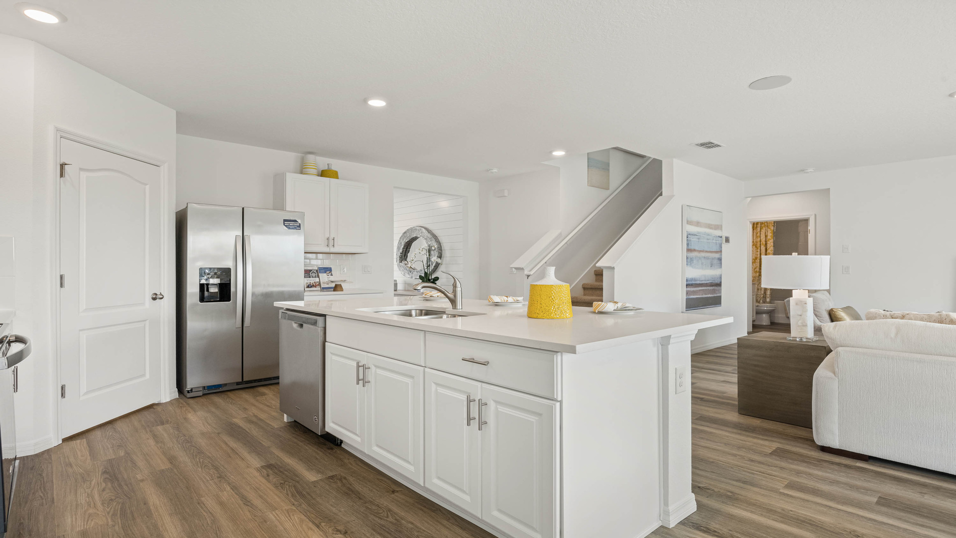 Kitchen with island seating, quartz counters, spacious pantry and stainless-steel appliances overseeing staircase
