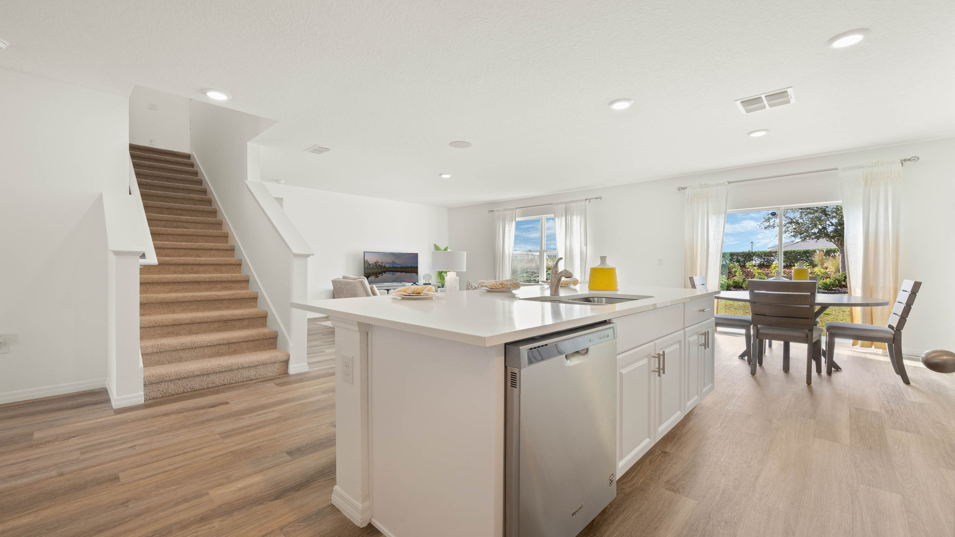 Kitchen with island seating, quartz counters, spacious pantry and stainless-steel appliances overseeing staircase