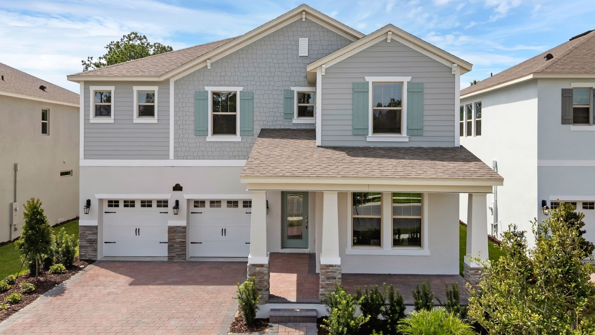 Two-story new home with driveway, large windows, and grassy front yard.