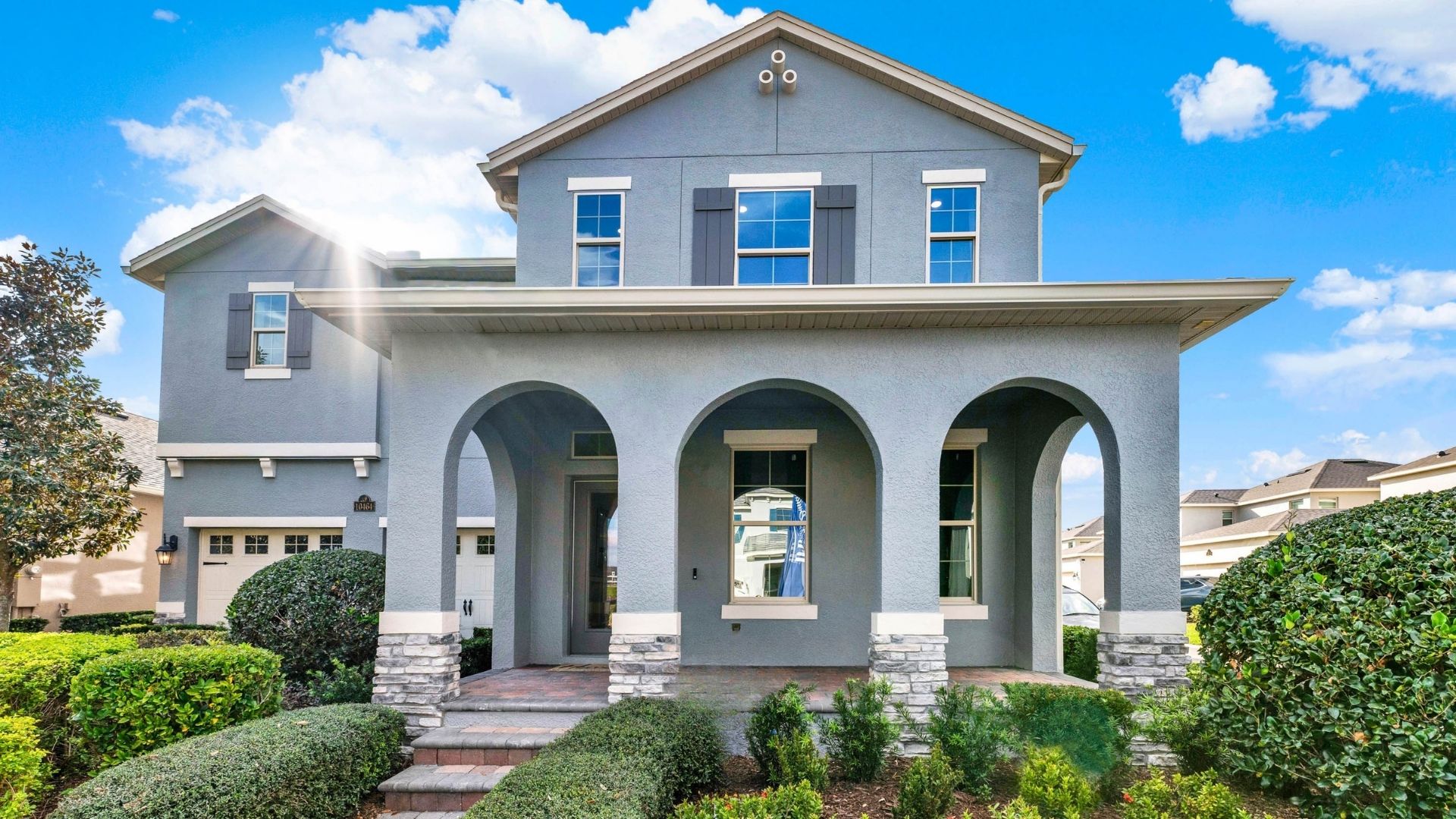 Two-story new home with driveway, large windows, and grassy front yard.