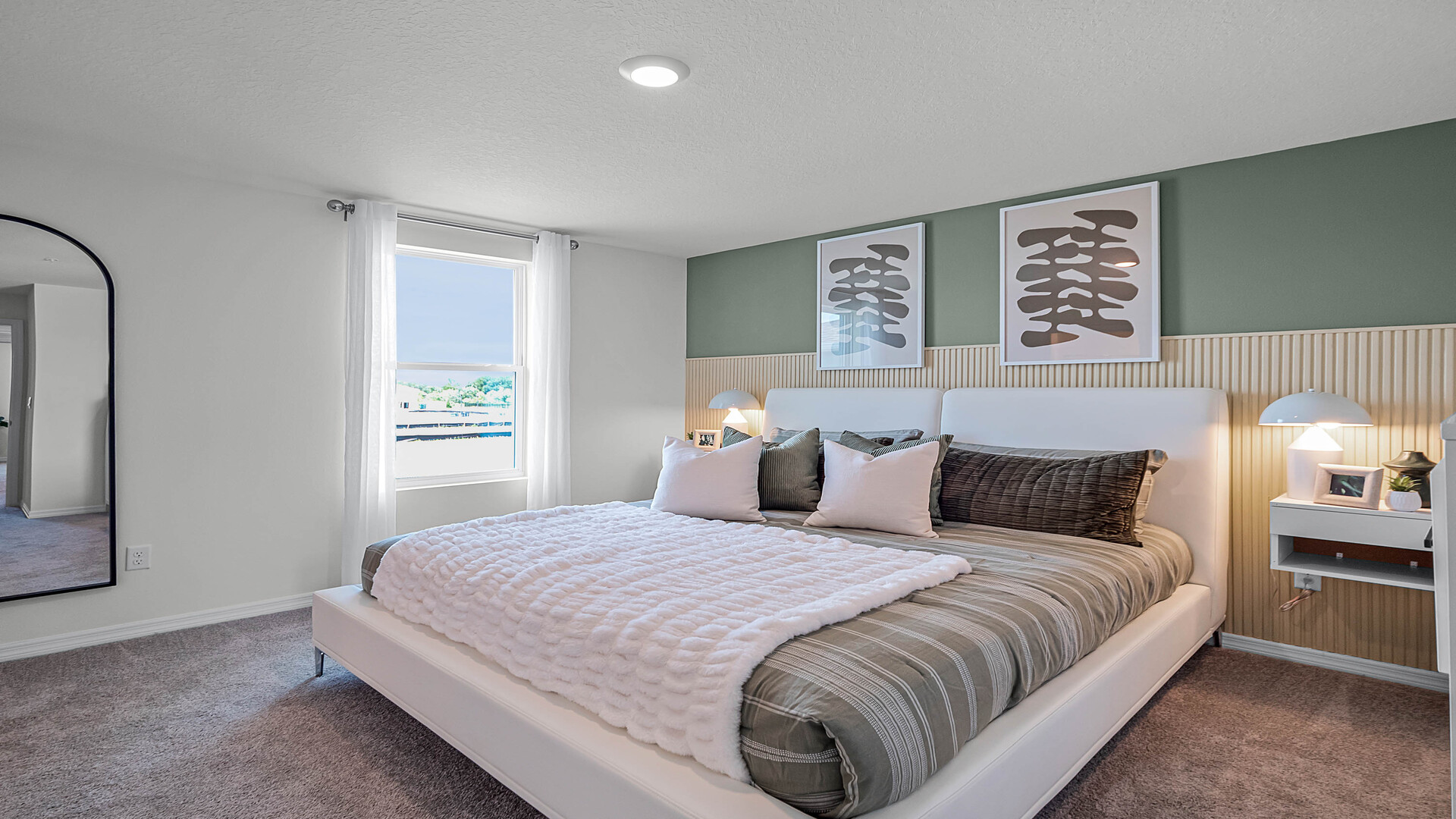 Spacious primary bedroom with king size bed, carpet flooring, natural lighting.
