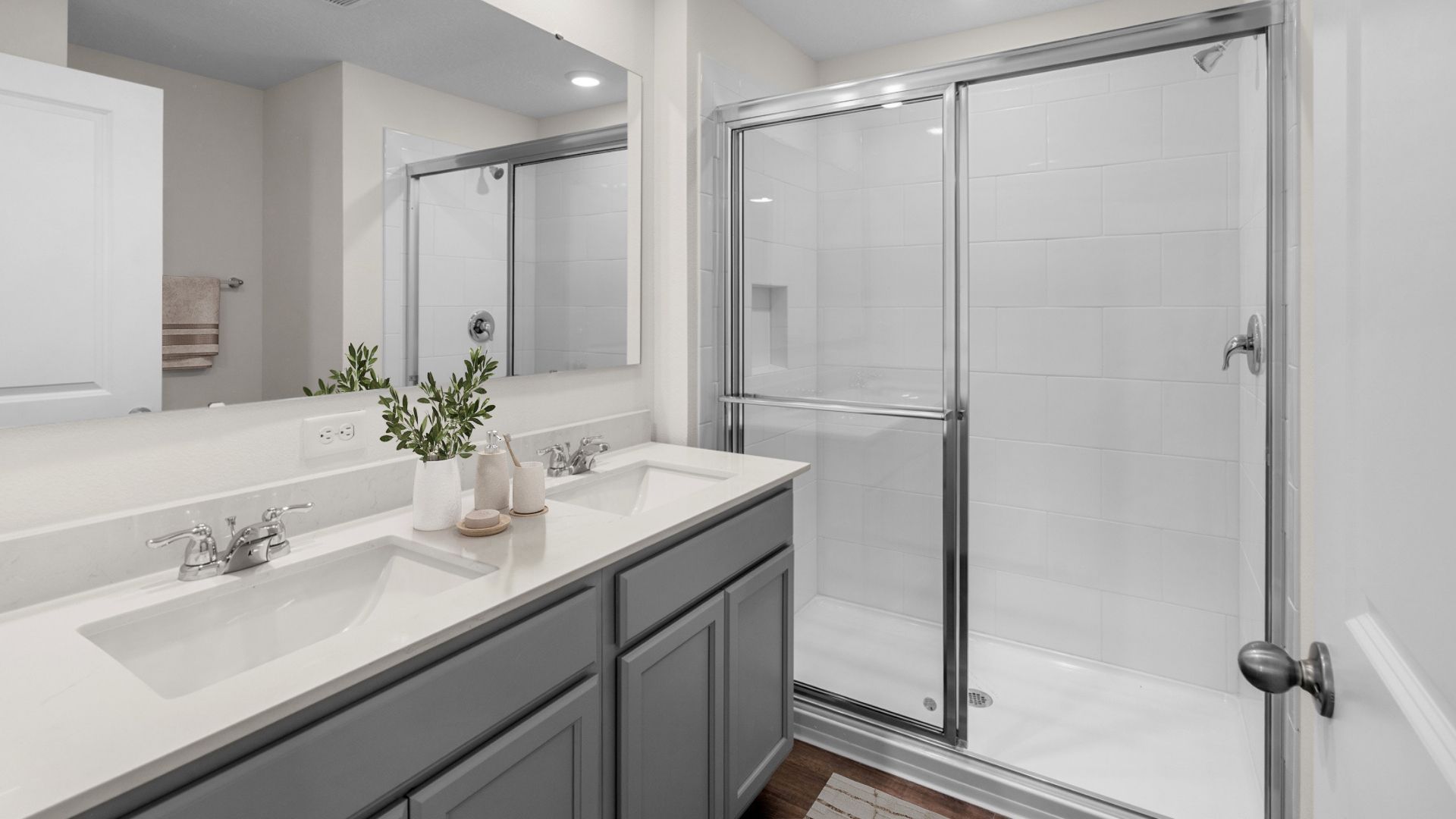 primary bathroom with quartz counters double sink and laminate flooring