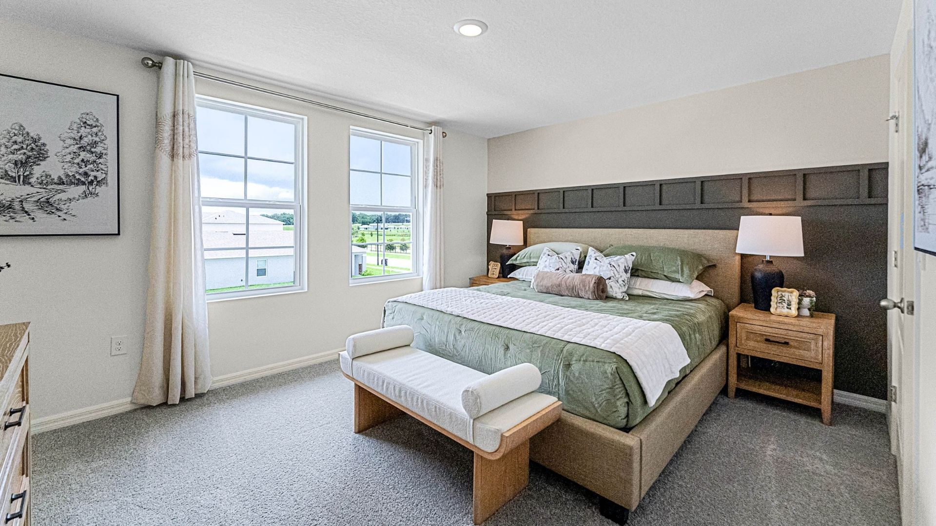 Spacious primary bedroom with king size bed, carpet flooring, natural lighting.