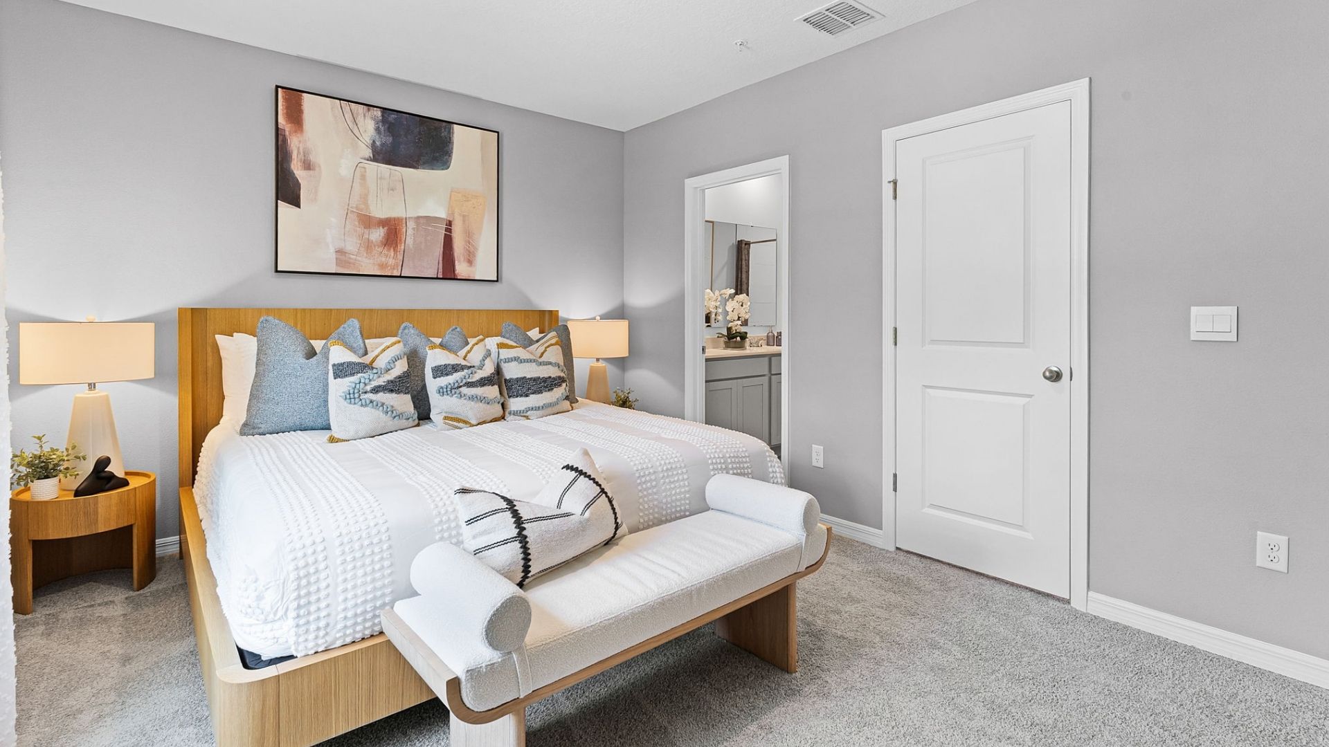 Spacious primary bedroom with king size bed, carpet flooring, natural lighting.