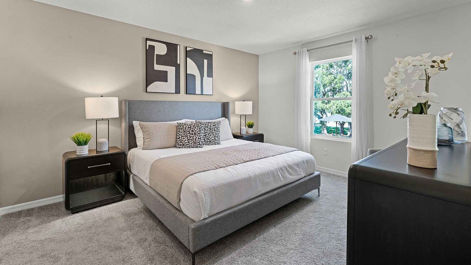 Spacious primary bedroom with king size bed, carpet flooring, natural lighting.