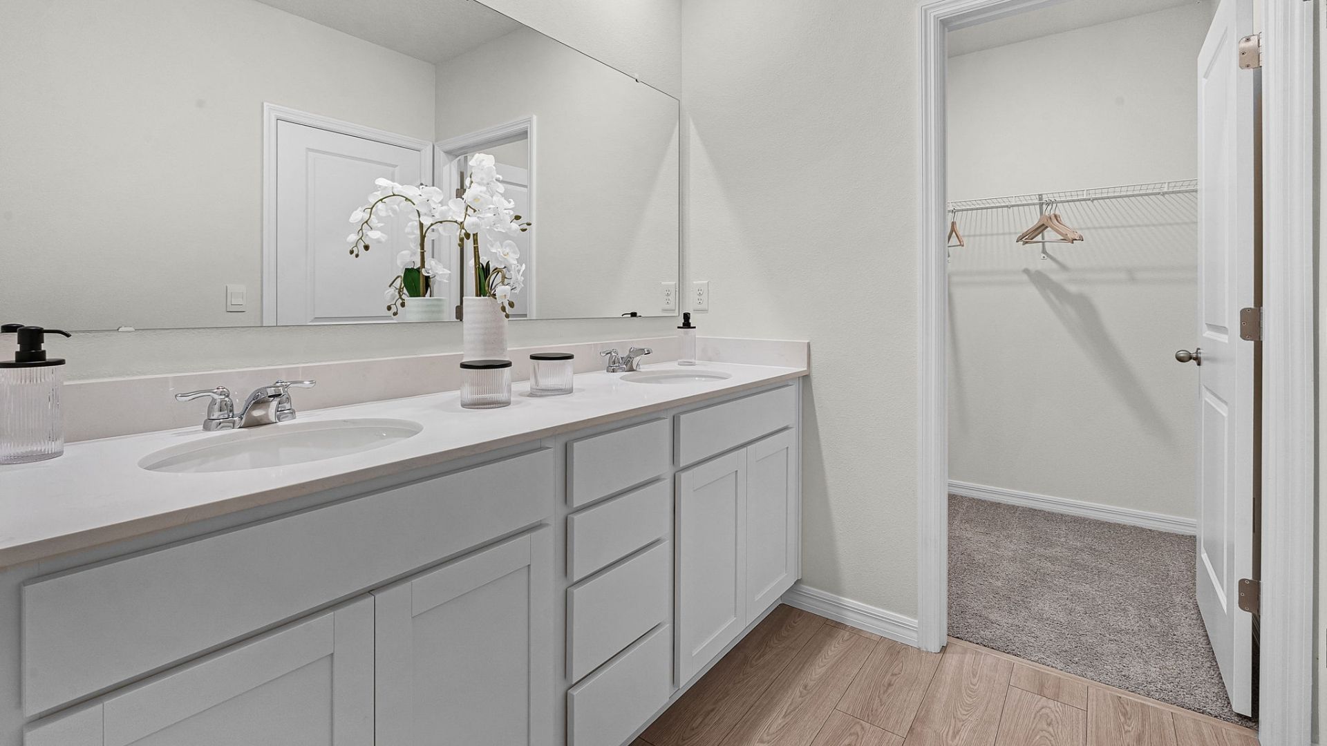 primary bathroom with quartz counters double sink and revwood select flooring