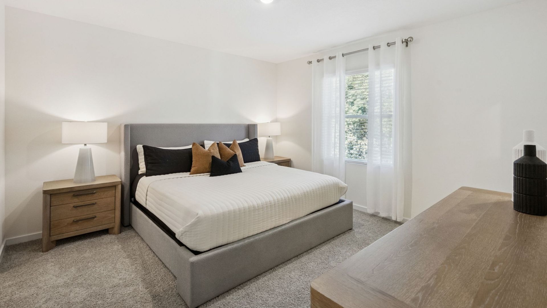 Spacious primary bedroom with king size bed, carpet flooring, natural lighting.