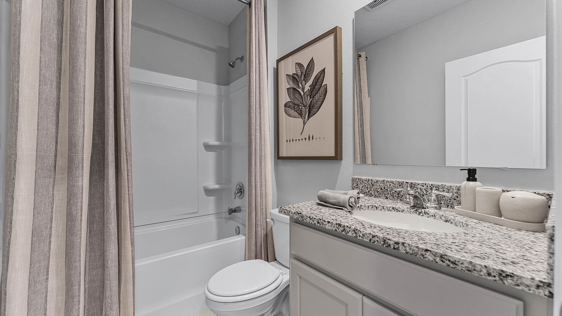 Modern bathroom with double vanity, large wall mirror, cabinets and granite countertops along with toilet and shower