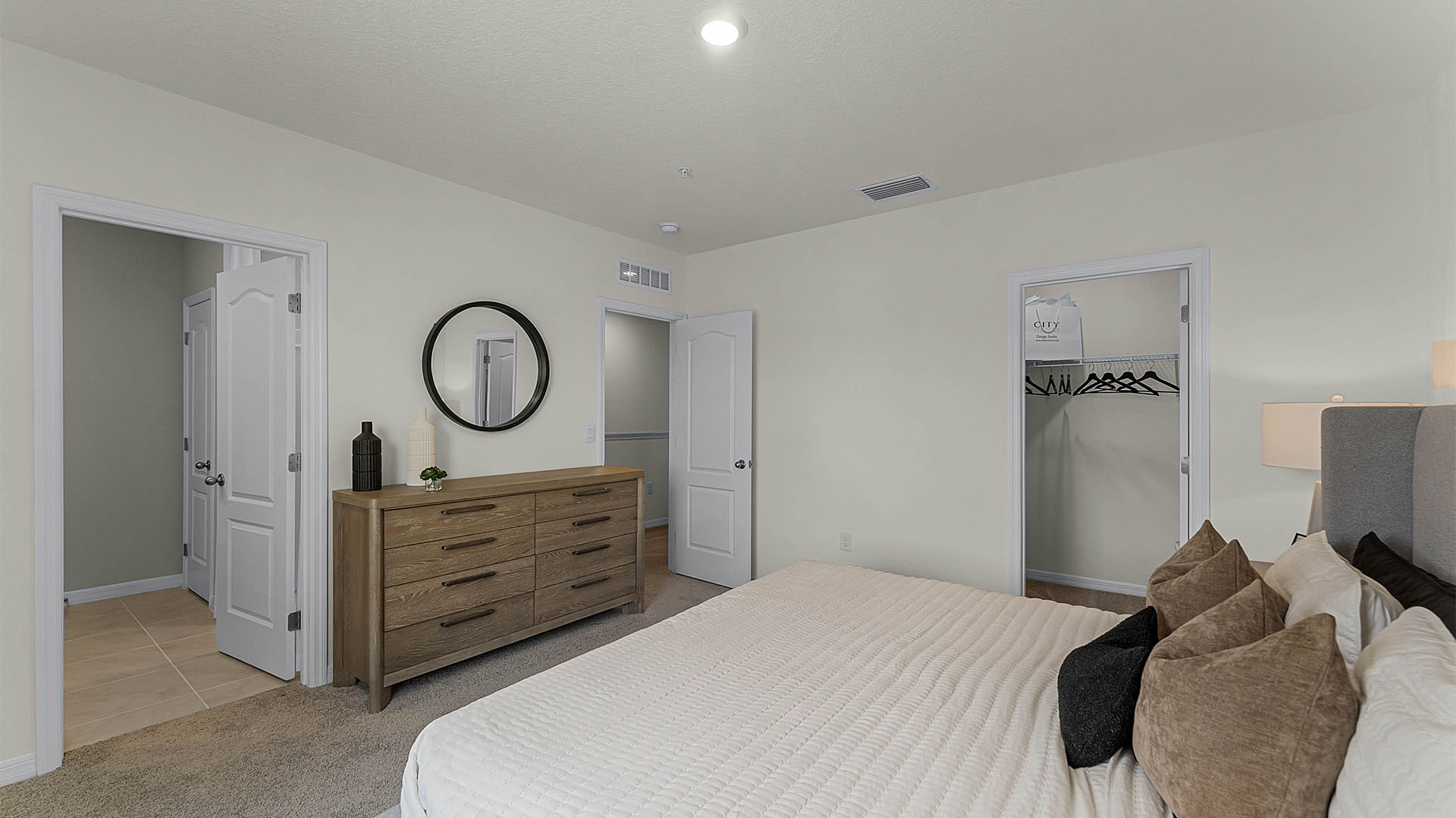 Spacious primary bedroom with king size bed, carpet flooring, natural lighting showing access to walk-in closet and master bathroom.