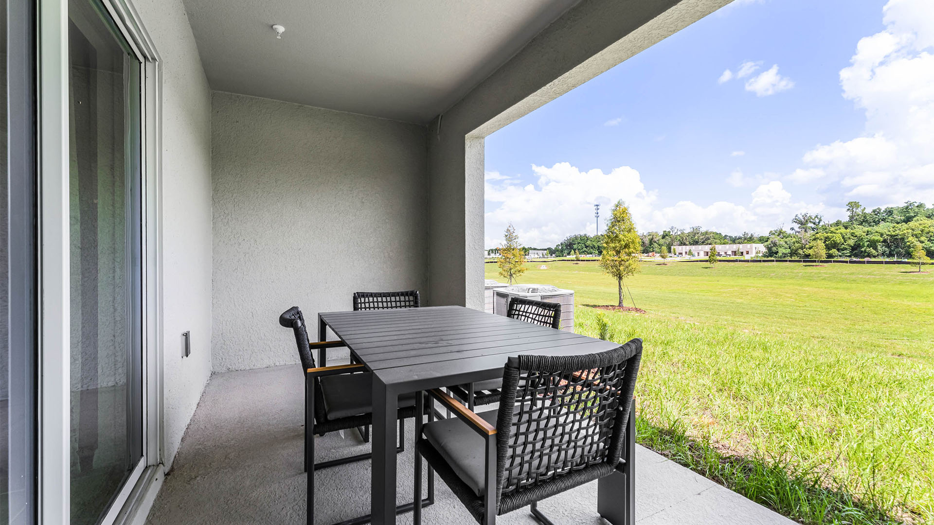 Rear of home with view of grassed backyard, porch seating and sliding doors.