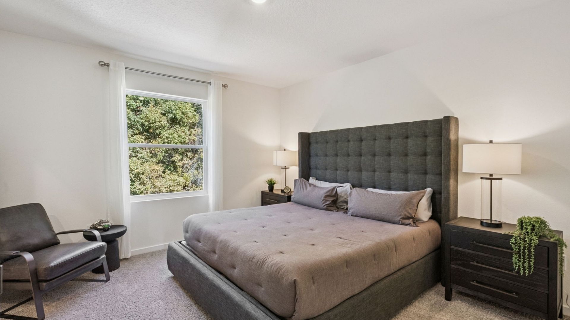 Spacious primary bedroom with king size bed, carpet flooring, natural lighting.
