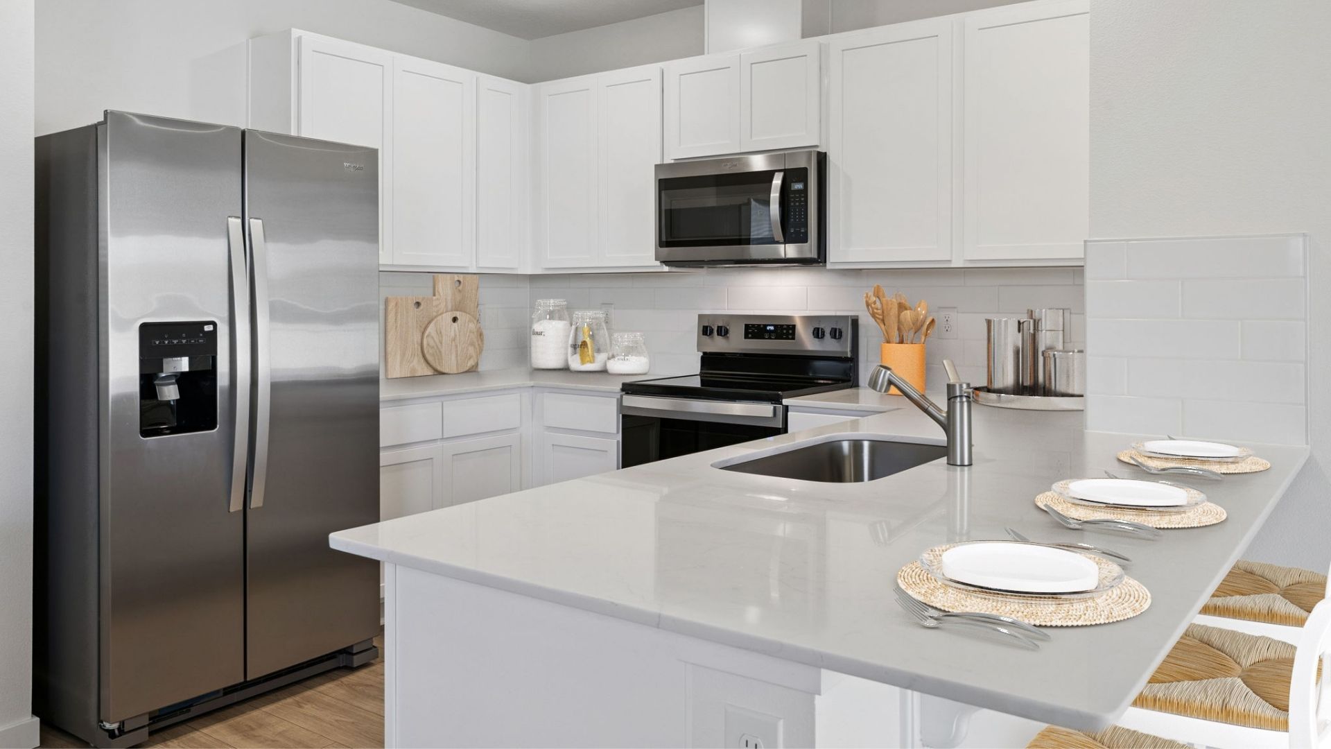 Kitchen with seating, quartz counters, spacious pantry and stainless steel appliances.