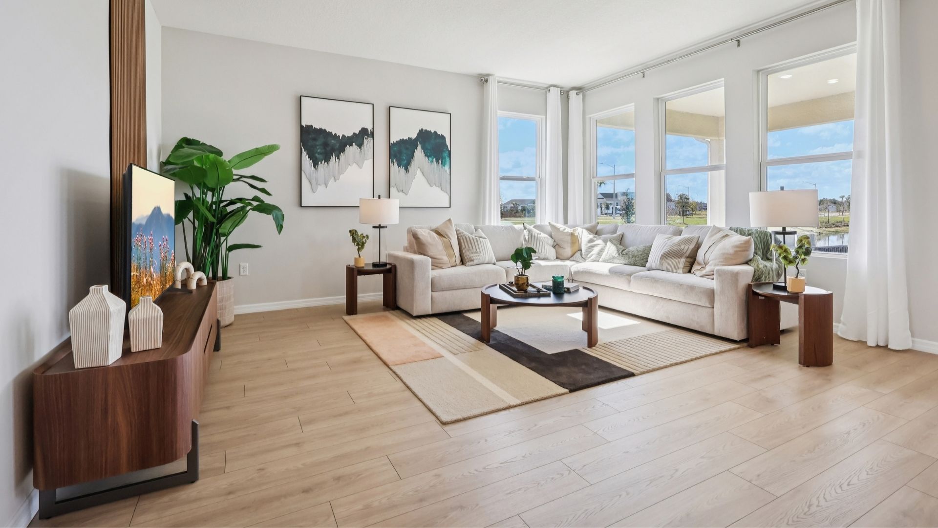 Living area with couch seating, natural lighting, laminate flooring.